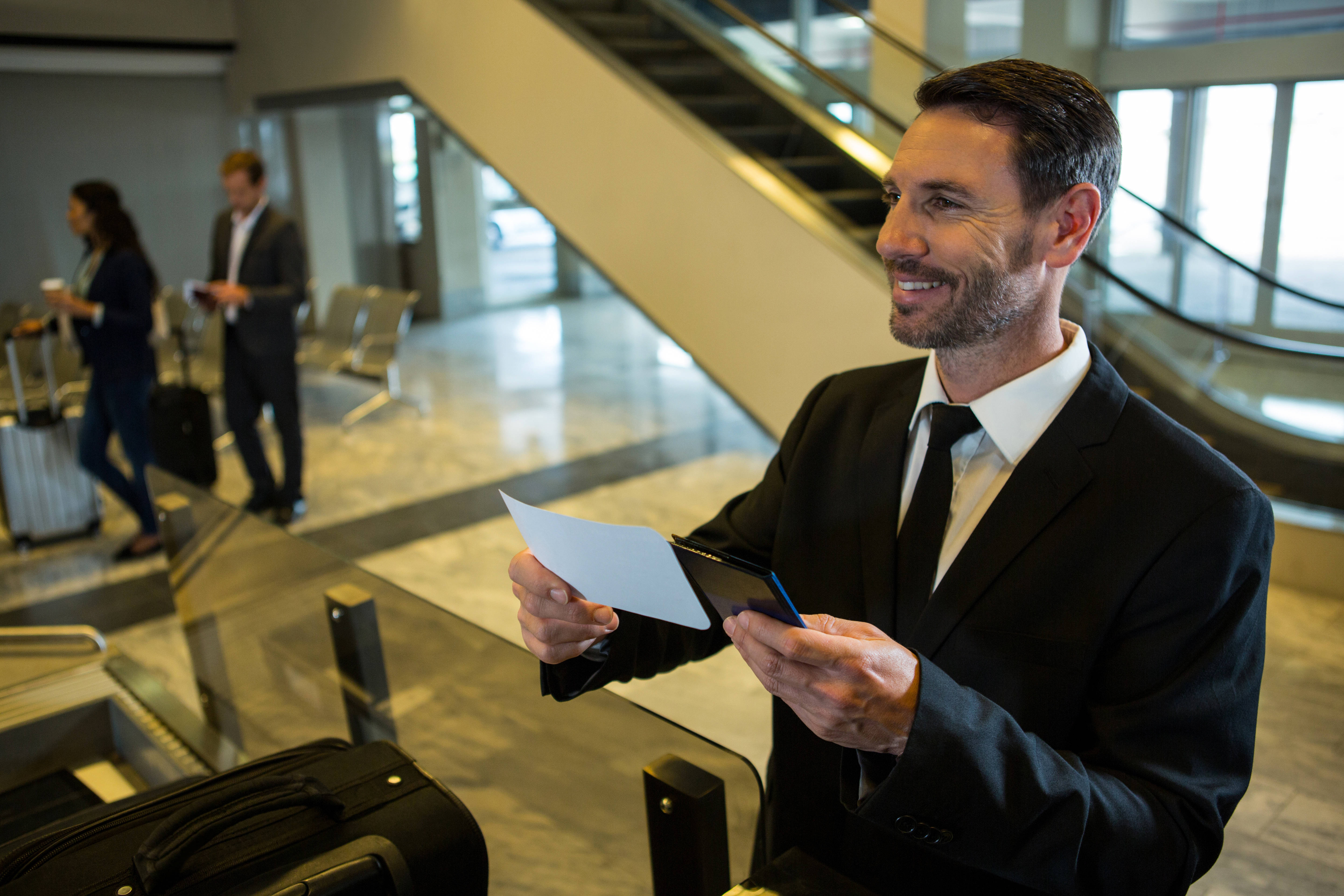 Businessman holding a boarding pass and passport, preparing for air travel