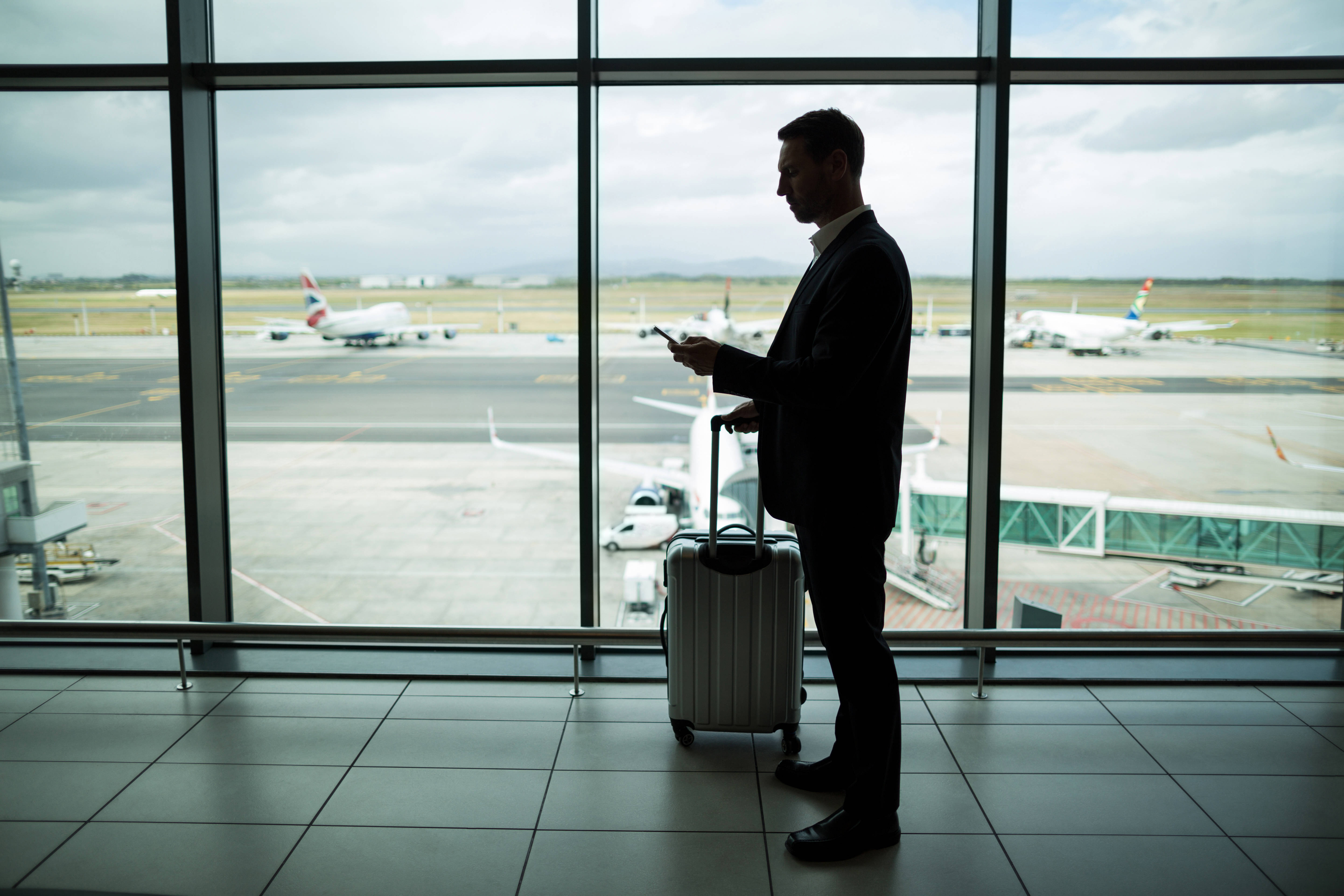 Businessman with luggage using mobile phone