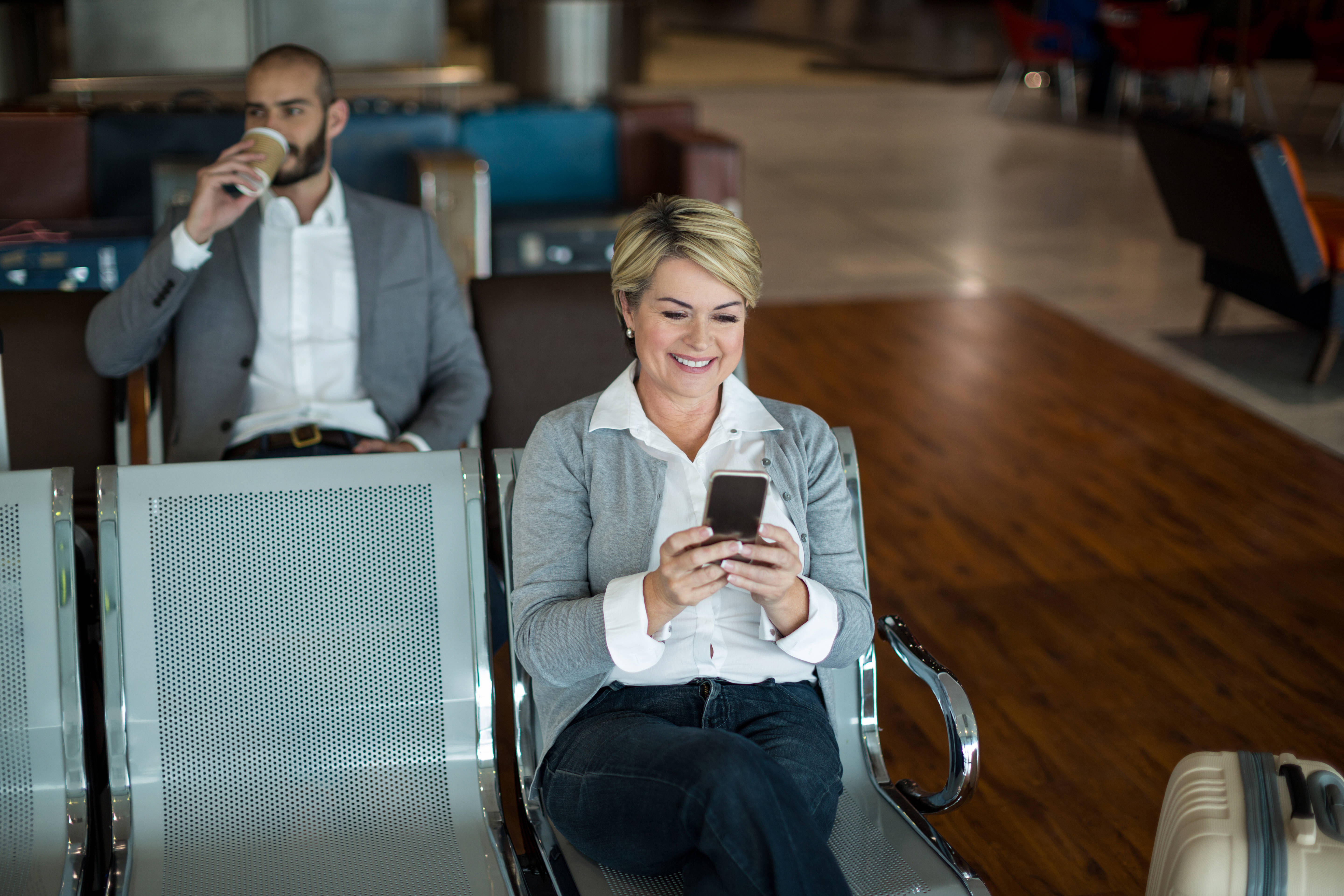 Businesswoman using mobile phone in airport waiting area