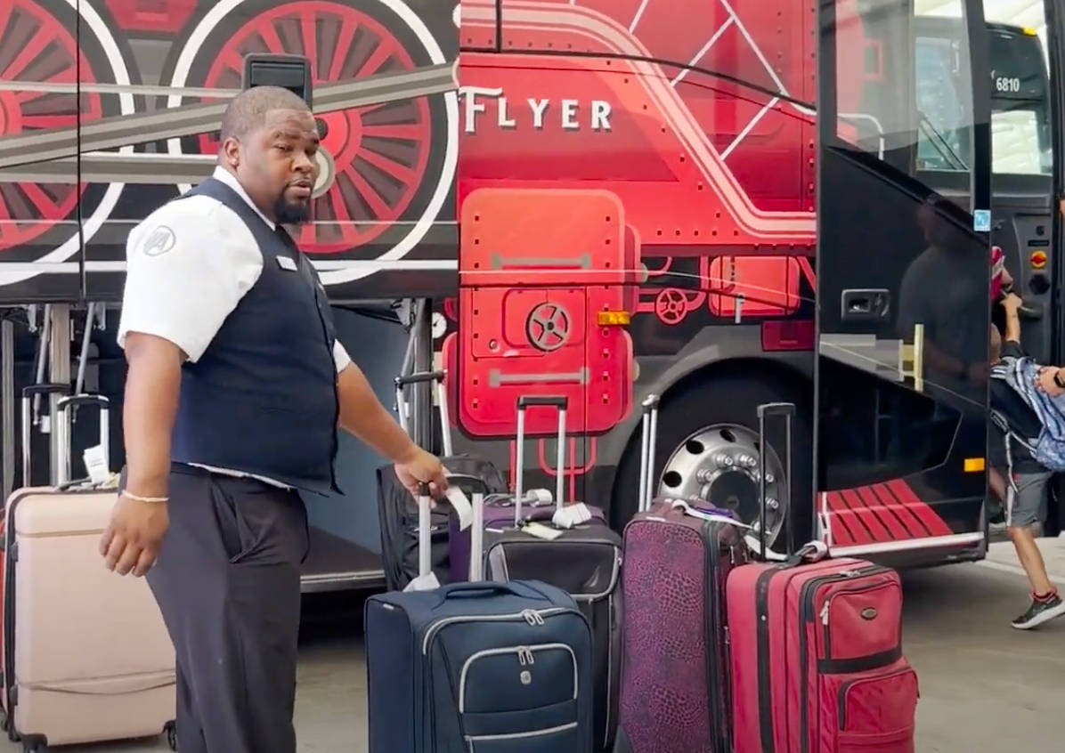 Bus driver loading luggage onto an airport shuttle bus