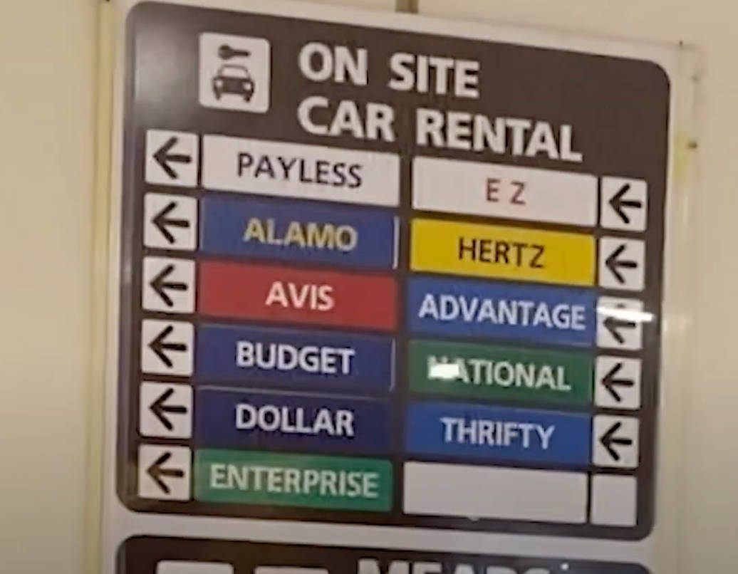 Sign indicating the location of airport rental cars with directional arrows