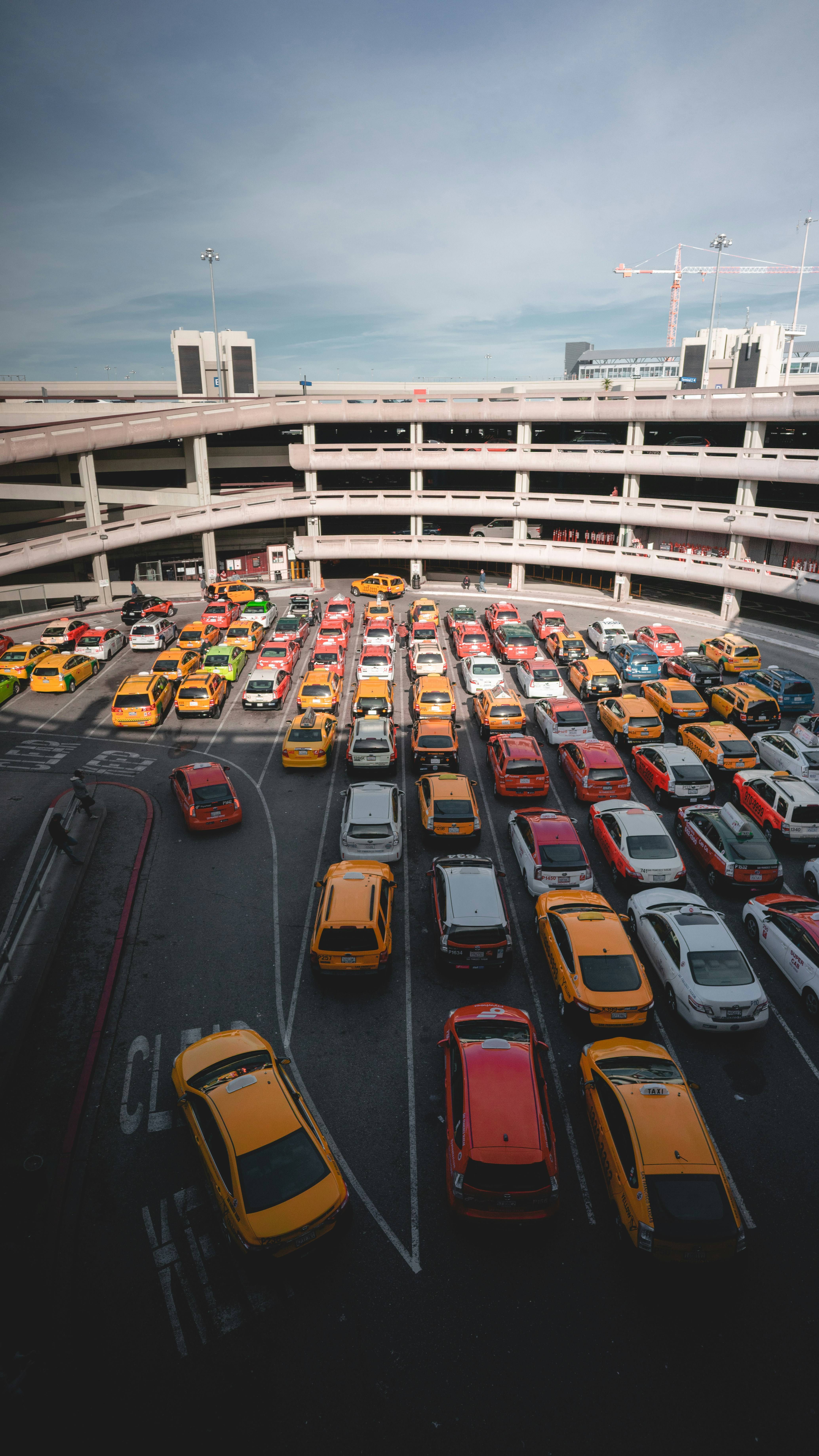 Different cars parked near white buildings in an airport parking lot