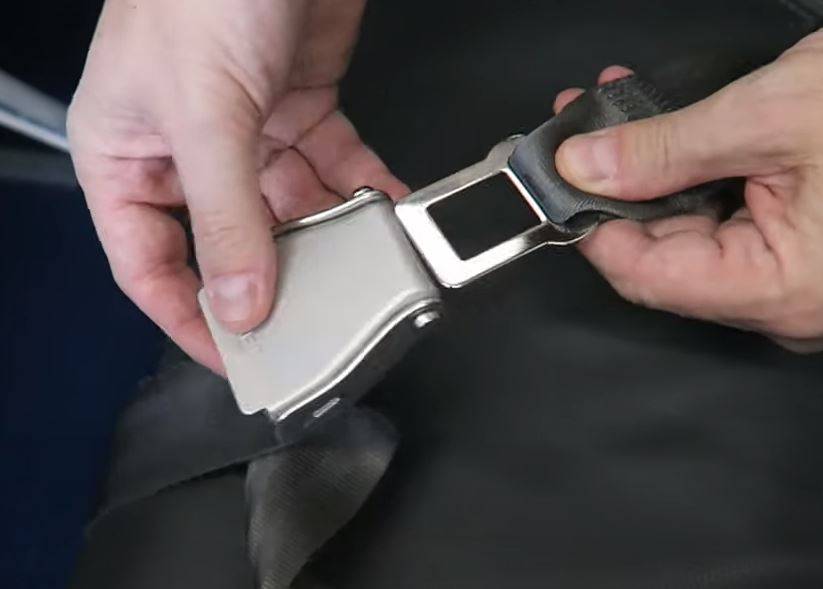 Person fastening their seatbelt in a commercial airline seat