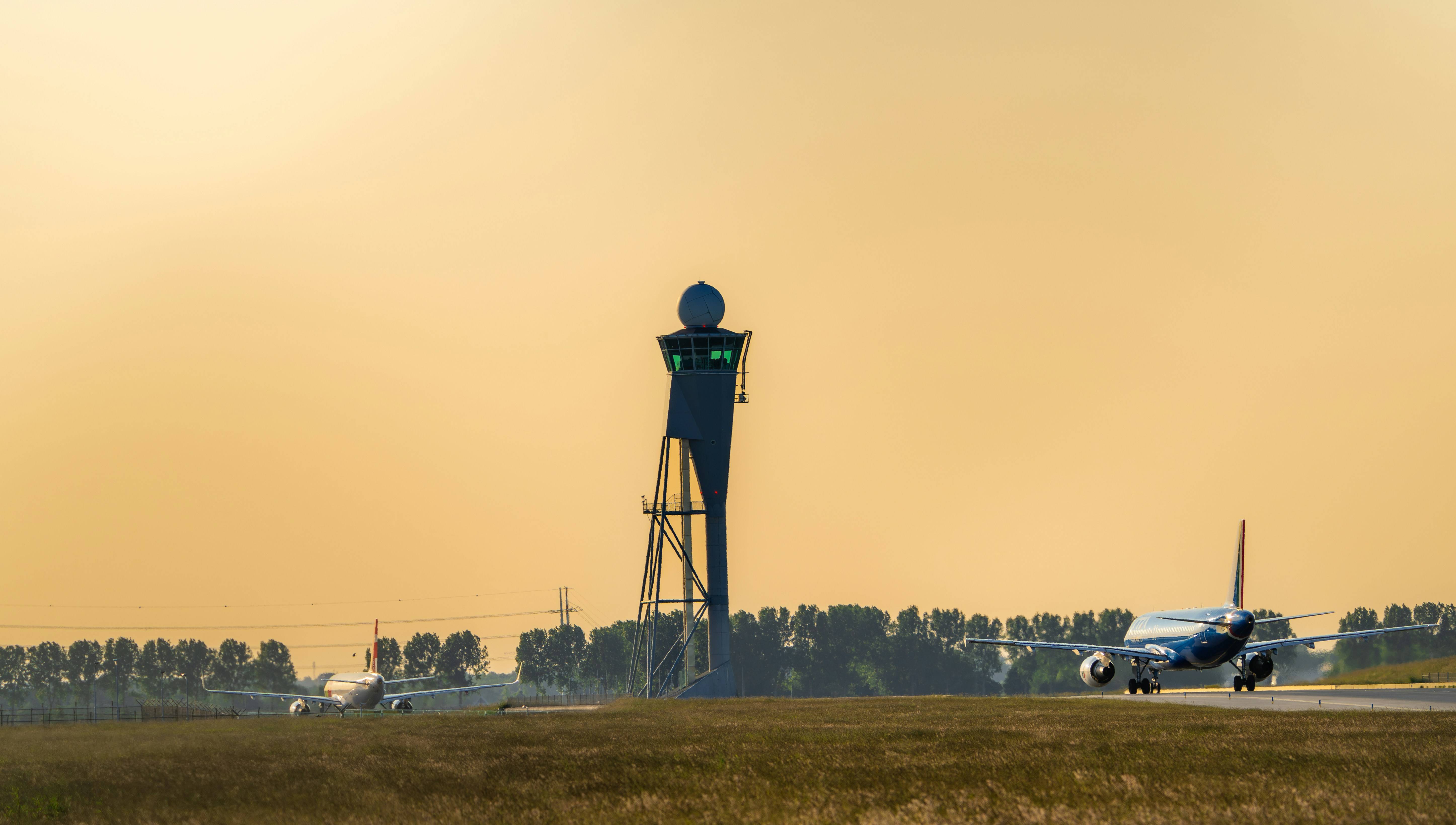 plane on a runway with a tower in the background