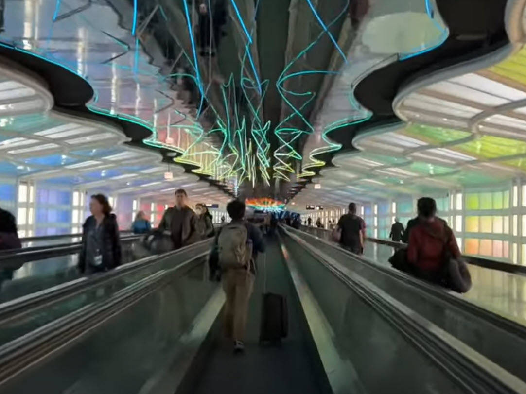 Travelers walking through light tunnel between Concourse A and B at ORD Airport